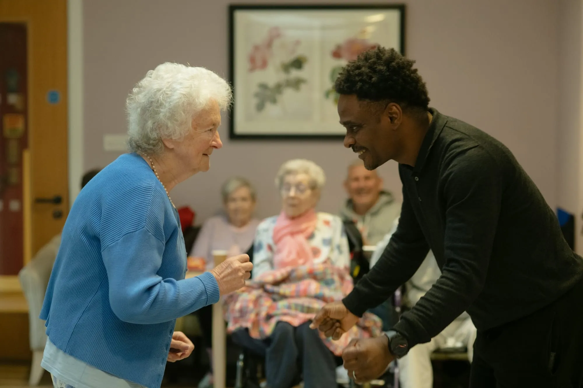 A young man dances with a smiling older woman