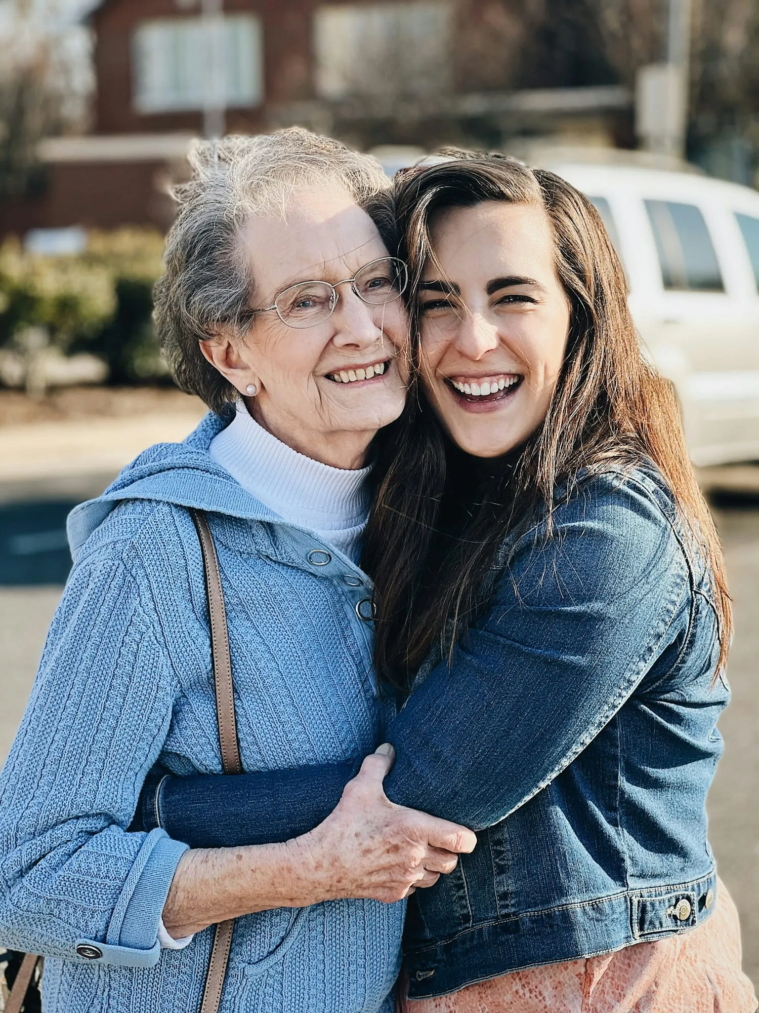 An older woman and her adult daughter share a warm hug outdoors